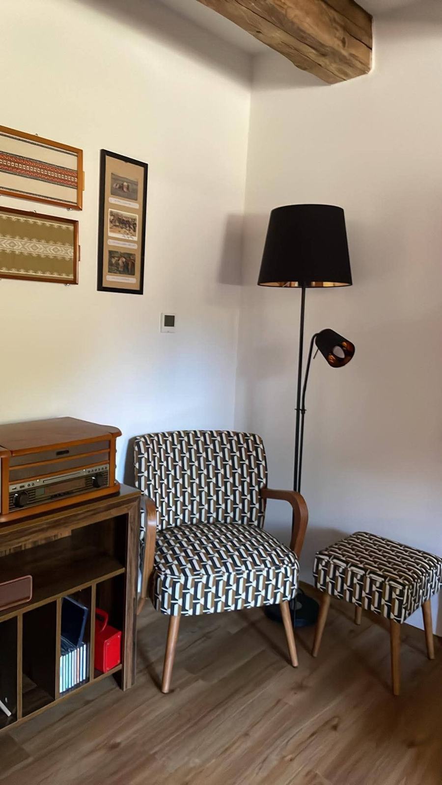 Dvě křesla se vzorovaným potahem, stojací lampa a gramofon na komodě