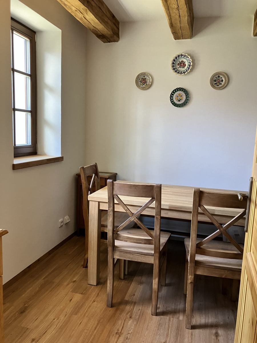 Dřevěný jídelní stůl se čtyřmi židlemi, na zdi malované talíře